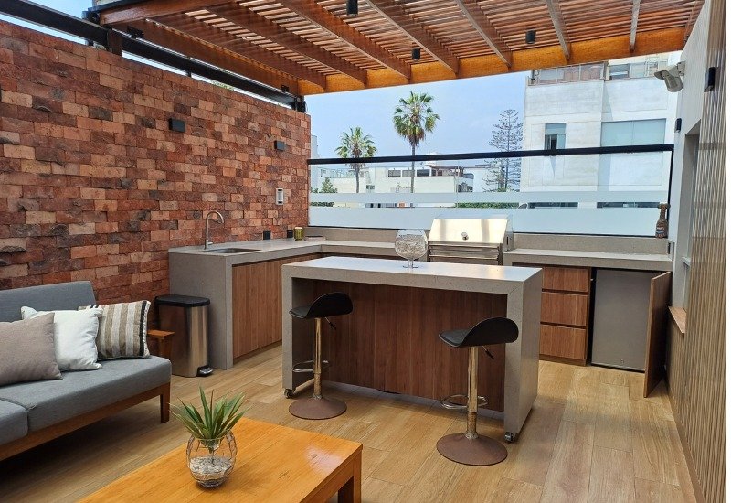 Terraza con cocina exterior y pergola de madera